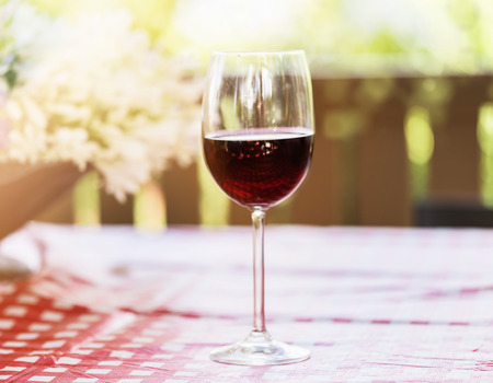 Single glass of red wine over natural background with hazy sunlight and bokeh. Selective focus, shallow Depth of fieldの写真素材
