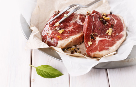 Red meat and fork over white wooden backgroundの写真素材