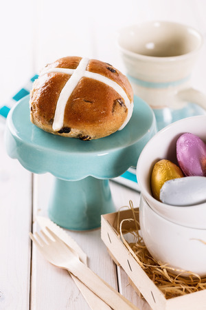 Tasty Easter cross-bun served on a cupcake stand on white wooden backgroundの写真素材