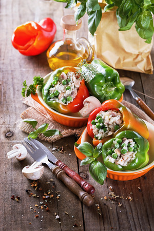 Colorful stuffed bell peppers with herbs and tableware on rustic wooden background. Selective focus, shallow depth of fieldの写真素材
