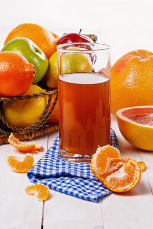 Colorful fruits in a basket and juice over white wooden backgroundの写真素材