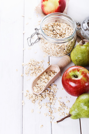 Fresh apples and pears and rolled oats over white wooden background. Selective focus, shallow DoFの写真素材