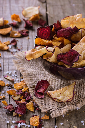 Healthy vegetable beetroot, sweet potato and white sweet potato chips on a bowl on a rustic background. Selective focusの写真素材