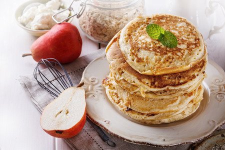 Stack of healthy low carbs oat pancakes over white wooden backgroundの写真素材