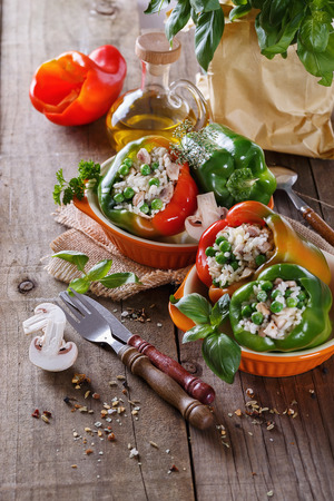 Green, red and orange bell peppers stuffed with rice and peas on rustic wooden background. Selective focus, shallow depth of fieldの写真素材