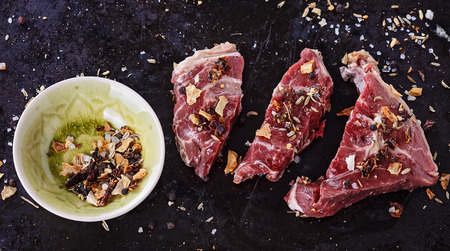 Red meat pieces and spices over rustic metal background. Top view, close up, selective focusの写真素材