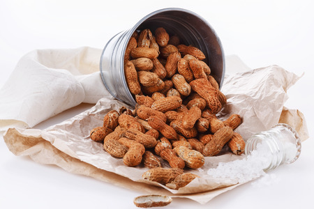 Roasted peanuts in shells in a metal bucket on a white background. Selective focus, close upの写真素材