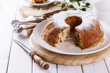 Homemade Bundt Cake with raisins dusted with icing sugar on a white plate over white wooden background. Selective focus, Shallow Depth of Field, Close upの写真素材