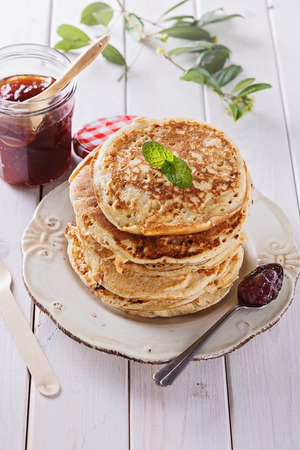 Stack of healthy low carbs oat pancakes and jam over white wooden backgroundの写真素材