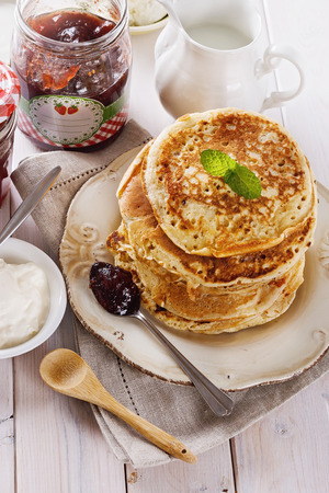 Stack of healthy low carb oat pancakes, jam and cream for breakfast over white wooden backgroundの写真素材