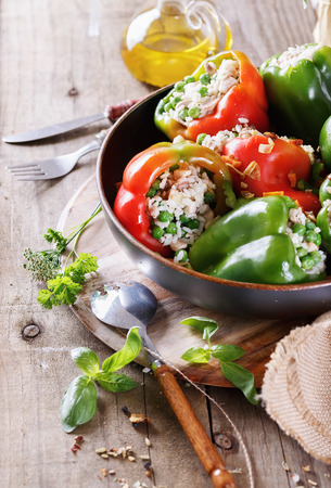 Colorful bell peppers stuffed with rice and peas, herbs and oil on rustic wooden background closeup. Selective focus, shallow depth of fieldの写真素材