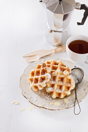 Homemade Belgian waffles dusted with icing sugar over white wooden backgroundの写真素材