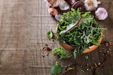 Leafy green mix of kale, spinach, baby beetroot leaves over rustic wooden backgroundの写真素材