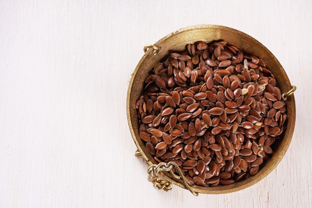 Top view of linseed in a weighing dish over white wooden background. Close up image with copy spaceの写真素材