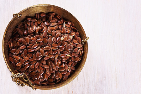 Top view of linseed in a weighing dish over white wooden background. Close up image with copy spaceの写真素材