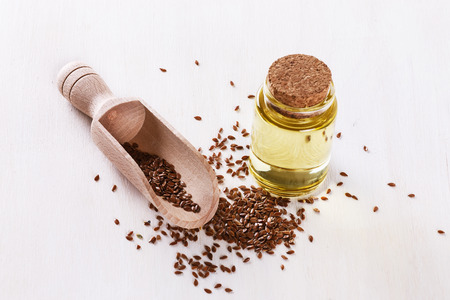 Linseed and bottled flaxseed oil over white wooden backgroundの写真素材