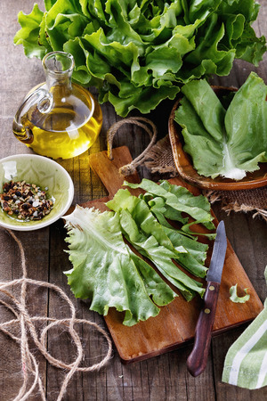 Cut up organic butter lettuce piece on a chopping board with knife over wooden rustic backgroundの写真素材