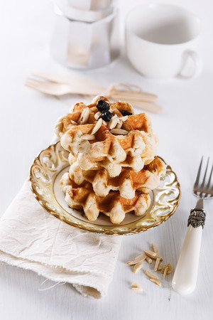 Homemade Belgian waffles with dry blueberries and shredded almond over white wooden backgroundの写真素材