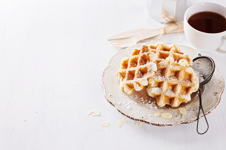 Belgian waffles dusted with icing sugar over white wooden background with copyspace. Selective focusの写真素材