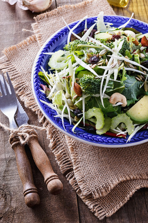 Colorful vegetable detox salad with nuts, seeds and dry berries over rustic wooden backgroundの写真素材