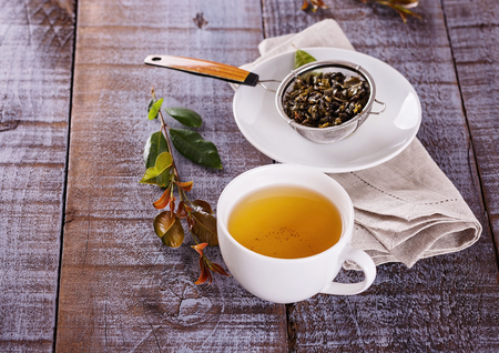 Green tea in a white ceramic cup over rustic wooden backgroundの写真素材