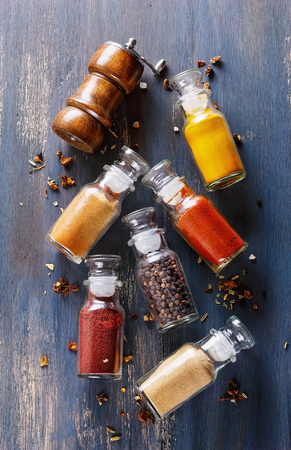 Collection of spices in glass bottles over rustic wooden background. Top viewの写真素材
