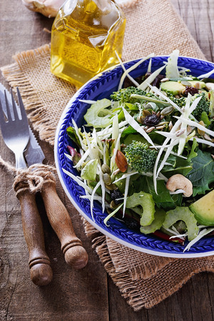 Green detox salad with nuts, seeds and dry berries over rustic wooden background closeupの写真素材