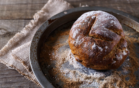 Homemade rustic bread on a baking tray over wooden backgroundの写真素材