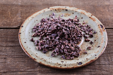 Raw Cacao Nibs in a ceramic plate over rustic wooden backgroundの写真素材