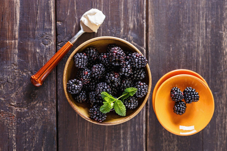 Fresh blackberries in a ceramic bowl over white wooden background. Rustic style, Top view, Selective focusの写真素材