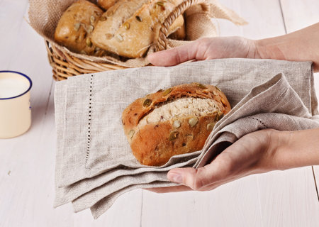 Hands holding ciabatta bread against white wooden background