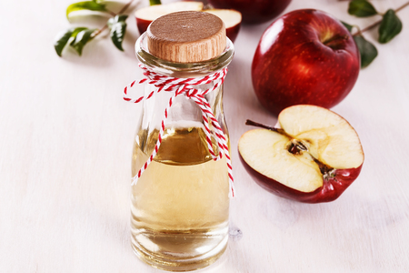 Apple cider vinegar and red apples over white wooden background. Selective focusの写真素材