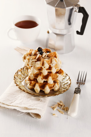 Homemade Belgian waffles with dry blueberries and shredded almond over white wooden backgroundの写真素材