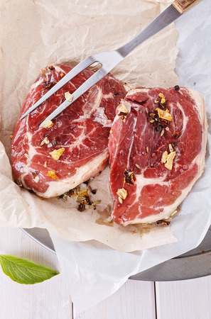 Two pieces of red meat, spices and fork close upの写真素材