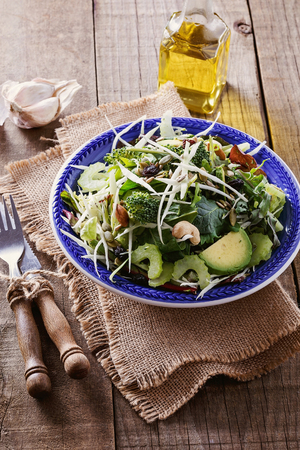 Green detox salad with nuts, seeds and dry berries over rustic wooden background closeupの写真素材