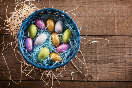 Top view of Chocolate Easter eggs in Easter themed basket over wooden background with copy space. Rustic styleの写真素材