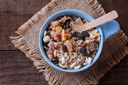 Top view image of bowl of healthy gluten free muesli with nuts and dried berries over rustic wooden background. Clean eating, Healthy living, Vegan, Vegetarian, Gluten free food conceptの写真素材