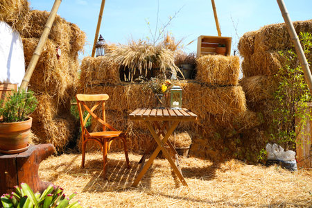Turn straw pile into a dining corner  by arranging a wooden table and chairs to match the color and texture of the straw.の写真素材