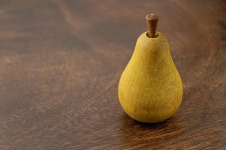 A wooden pear on dark wooden surfaceの写真素材