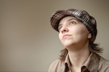 Young green eyed woman daydreaming in checked capの写真素材