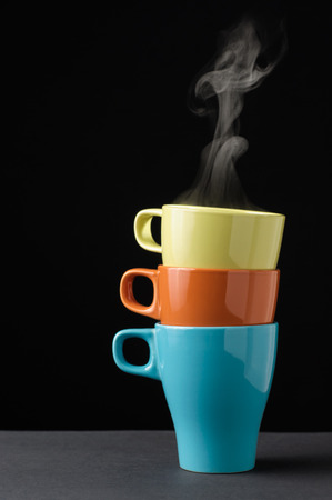 Three colorful mug with steam on top of one anotherの写真素材