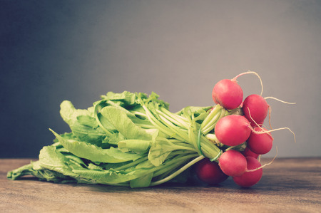 A bunch of fresh radishes on brown wooden tableの写真素材
