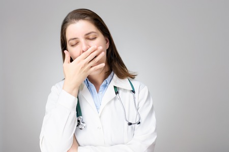 Portrait of a tired, yawning female doctorの写真素材