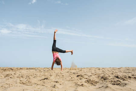 Girl doing a cartwheel in the sand on the beachの写真素材