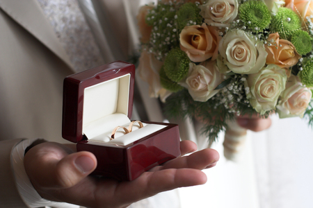 Groom holds wedding rings boxの写真素材