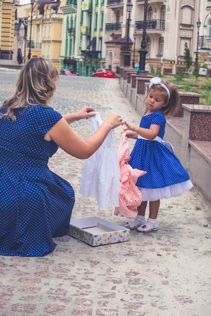 Mom puts a little girl on her head with a white headband with a flower.の写真素材