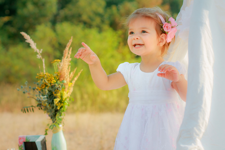 Little girl smiles and shows finger upward. A girl in a white Wigwam or play tent, childrens play houseの写真素材