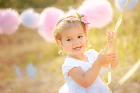 Happy baby on birthday celebration. A girl in a white dress smiles against.の写真素材