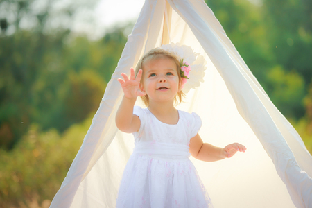 Girl in a white dress is pointing to something.の写真素材