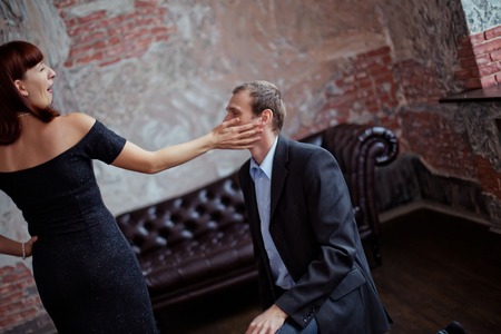 A woman is slapping a man. Wife swung at her husband. Family drama. Family scandal. Conflict in the family.の写真素材